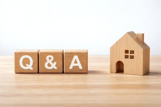 住宅購入や不動産投資の疑問を解決する木製ブロックのQ&Aロゴと家型のオブジェの背景