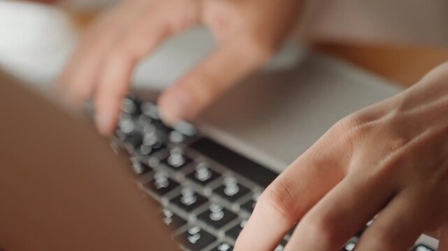 Caucasian hands typing on laptop keyboard in hotel room closeup, focused fingers pressing illuminated keys, warm ambient lighting, tactile motion and fast rhythm, work and booking activity