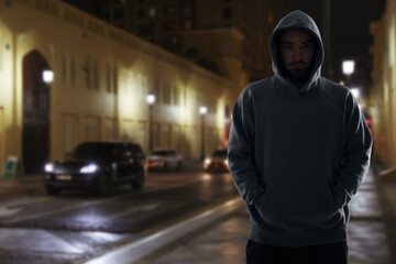 Fototapeta premium Criminal in hooded sweatshirt in city at night
