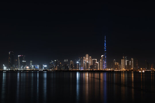 Stunning Dubai skyline at night, skyscrapers, luxurious hotels, futuristic architecture, and dynamic neon lights reflecting on the water.