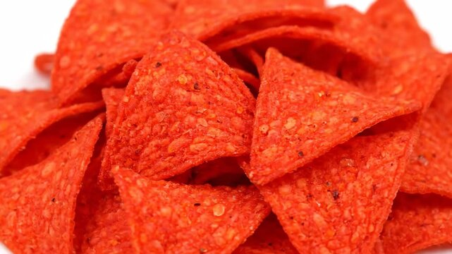 Close up view of a pile of spicy red corn tortilla chips. Savory junk food appetizer for a party or gathering. Unhealthy snack food with a crunchy textured surface and seasoning