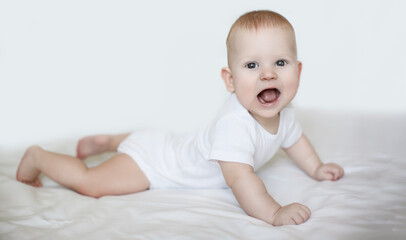 A young child with red hair is lying on a white surface and smiling broadly, exhibiting joyful play.