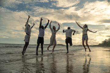 Silhouettes group multiethnic friends jumping together on beach at sunset celebrating success enjoying freedom summer vacation