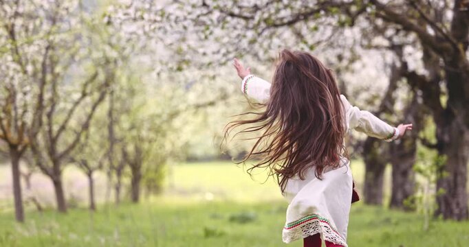 Carefree bulgarian girl running in blooming garden of fruit trees, the beauty of nature in Bulgaria