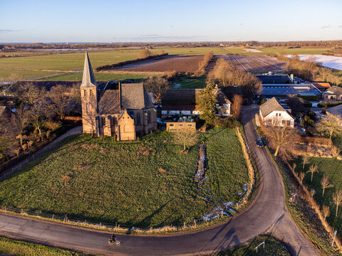 Aerial view of a quaint church standing proudly atop a grassy hill, its spire reaching towards the heavens, Church, Gelderland, Netherlands.