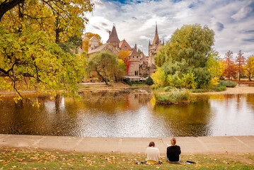 Fototapeta premium Autumn landscape in the park, two girls drawing by the lake