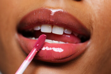 Naklejka premium Close up of lips applying glossy pink lip gloss with applicator mouth beauty