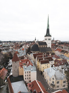 Aerial view of red-tiled roofs contrasting with the stark white spire of St. Olaf's Church piercing the skyline, Tallinn, Harju County, Estonia.