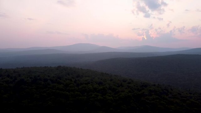 Aerial sunset video of rolling green mountain ridges and dense forest in Maidstone, Vermont.