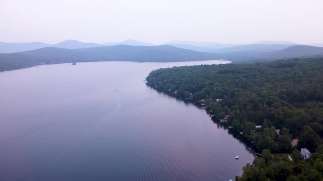 Aerial video of Maidstone Lake surrounded by dense green forest under a twilight sky, Vermont, USA.