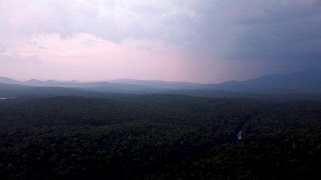 Aerial sunset video of rolling green mountain ridges and dense forest in Maidstone, Vermont.