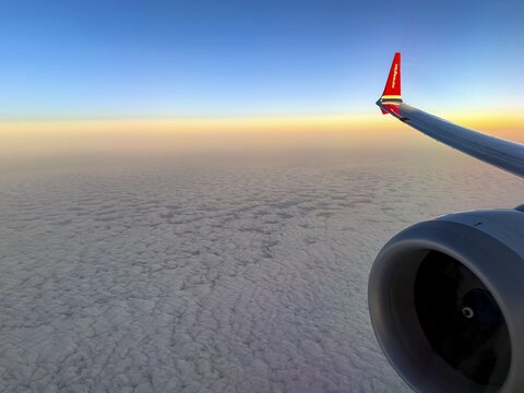 Airplane wing over sea of clouds in morning light, aerial view, Finland