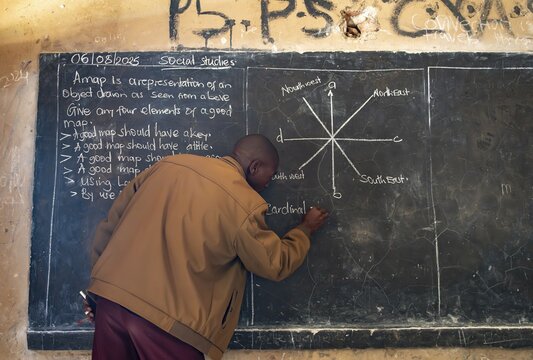 Teacher writes on a blackboard in a classroom during a lesson, school, Rushaga, Western Region, Uganda