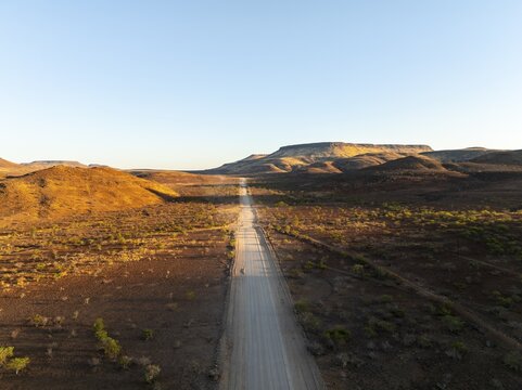 Aerial view, infinite space, straight road leads through dry desert landscape, hills in Damaraland, Namibia