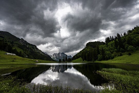 Gr&ouml;ppelensee with reflection of the Altmann summit in the background under a threatening cloudy sky, Wildhaus, Appenzell, Switzerland