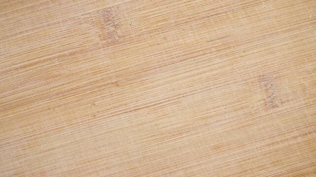 Rotating bamboo cutting board texture background. Smooth kitchen surface spinning slowly with visible knife marks and natural grain pattern