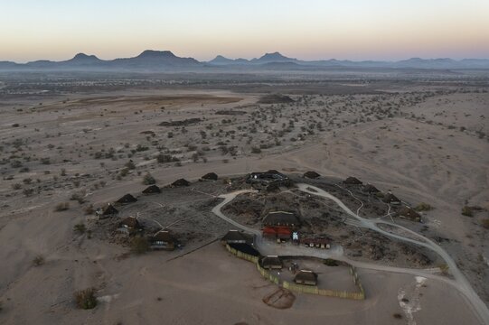 The Doro Nawas Camp and arid desert plains at the edge of the dry river bed of the Aba-Huab river, at dawn, aerial view, drone shot, Damaraland, Kunene Region, Namibia