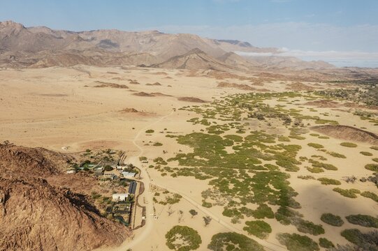 The Brandberg White Lady Lodge at the edge of the dry river bed of the Ugab river, in the background the Brandberg, Namibia's highest mountain, aerial view, drone shot, Damaraland, Erongo Region, Namibia