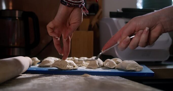 Hands finishing dumpling edges with fork for authentic homemade look
