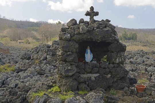 Lava rock and statue of the Virgin Mary at the foot of Mount Etna, Sicily, Italy