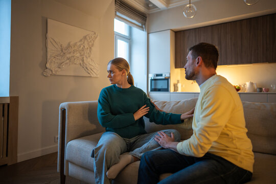 Betrayed frustrated woman in family quarrel with cheating husband, sitting on sofa having serious talk about love affair and disgusted by manipulative male lies, toxic relationship and disagreement.