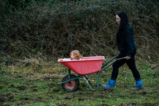 A curly red-haired girl in a red wheelbarrow in rural Ireland 