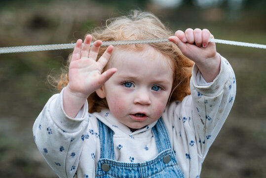 An intense and cute look by a little girl lifting a fence wire to get underneath on a farm