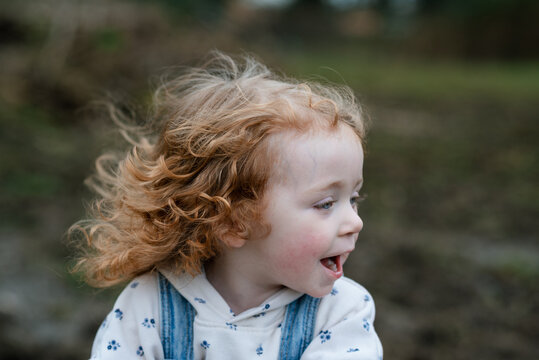 Curly red-haired girl showing excitement on a windy day
