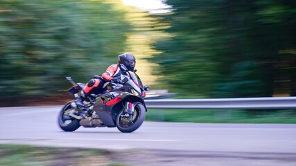 Sportbike rider leaning into a corner on a mountain road with motion blur effect © Igor