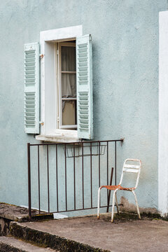 Vieille chaise rouill&eacute;e devant une maison bleue. Absence devant une fa&ccedil;ade