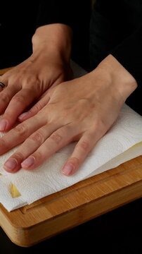 Woman patting raw potato slices with a paper towel to dry them for cooking, food preparation in the kitchen
