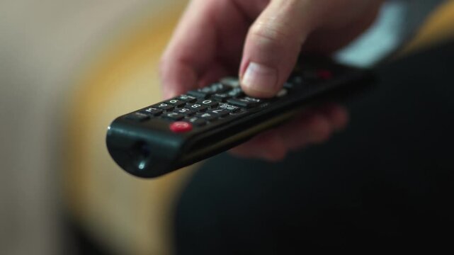  Close-up of Hand Switching TV Channels with Remote Control.