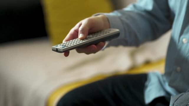  Close-up of Hand Switching TV Channels with Remote Control.