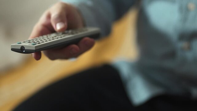 Close-up of Hand Switching TV Channels with Remote Control.