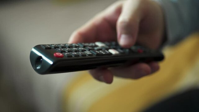  Close-up of Hand Switching TV Channels with Remote Control.
