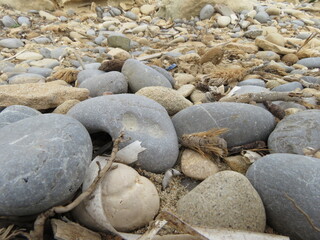 Close up of pebbles on a pebble beach with rocks
