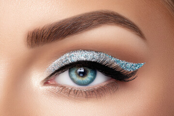 Naklejka premium Close up icy blue glitter eyeliner on female eye with long lashes for beauty makeup detail and cosmetic advertising closeup