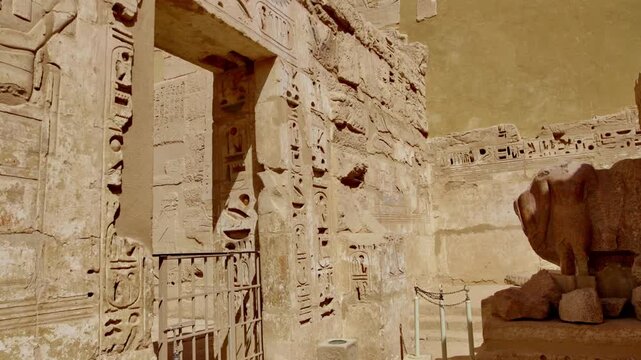 Closeup of ancient Egyptian hieroglyphic inscriptions with cartouches and bird symbols carved in sandstone wall at Medinet Habu temple in Luxor Egypt, detailed royal text.