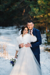 Naklejka premium young couple, the bride and groom, taking a winter walk in forest
