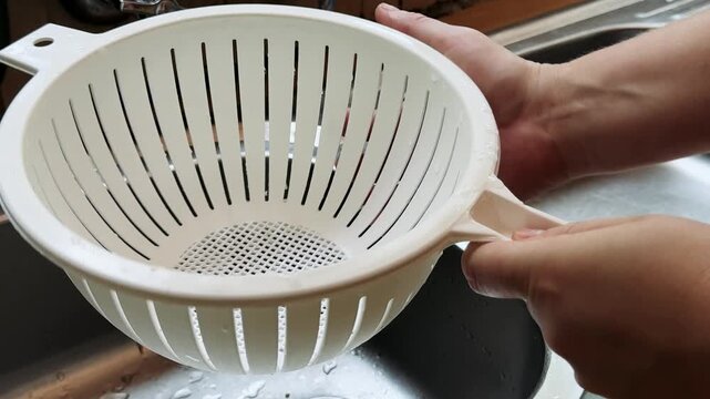 white colander is washed in the sink