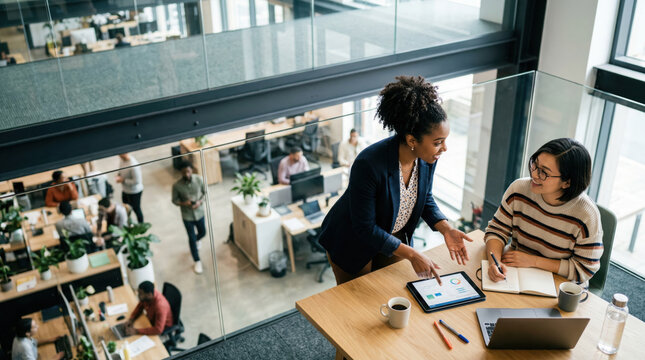 Two diverse businesswomen talking in an open office.
