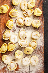 Fototapeta premium Raw ravioli pasta cooking flour and dough on the table tasty snack fresh delicious gourmet food background on the table rustic food top view copy space