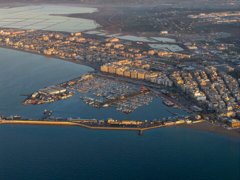 Aerial view of the sun-kissed harbor embracing a multitude of boats, contrasting the urban sprawl against the calm sea, Santa Pola, Valencian Community, Spain.
