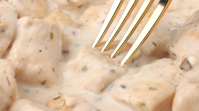 Chicken breast in mushroom cream sauce taking with fork close up