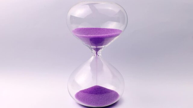 Transparent hourglass with flowing purple sand on white background. Old classic timer. Time concept
