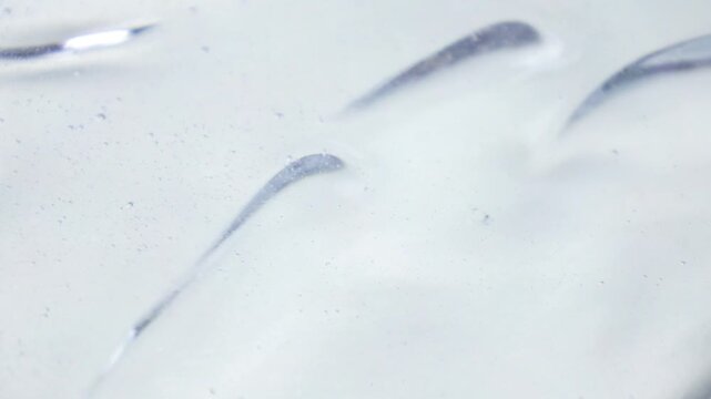Transparent cosmetic liquid gel with bubbles waves flowing close up
