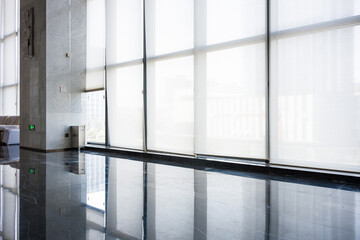 Naklejka premium Modern office lobby with floor-to-ceiling windows and polished marble flooring