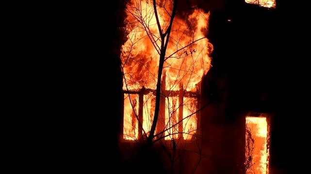 The window of the house is on fire, the night flame of the disaster. The natural wild flame is burning the building from the inside.