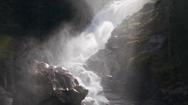 Breathtaking drone footage capturing the sheer power of Krimmler Wasserf&auml;lle in the Austrian Alps. Golden sunlight pierces through the misty spray against vibrant mossy rocks