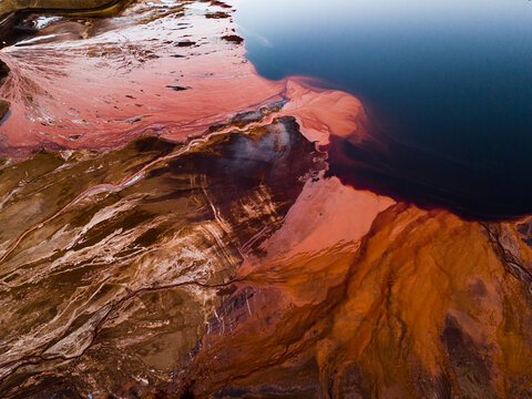 Aerial view of a striking contrast between the deep blue water and the reddish-brown earth, creating a surreal landscape, Aluminium Refinery, Western Australia, Australia.